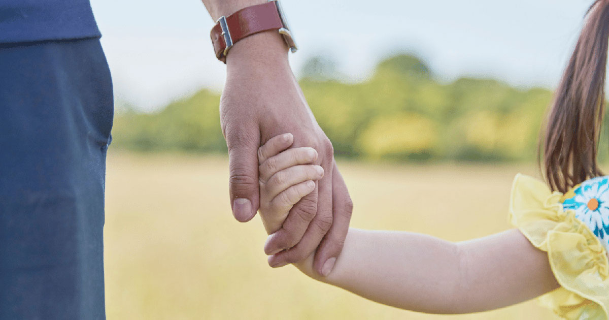 Father and young child hold hands